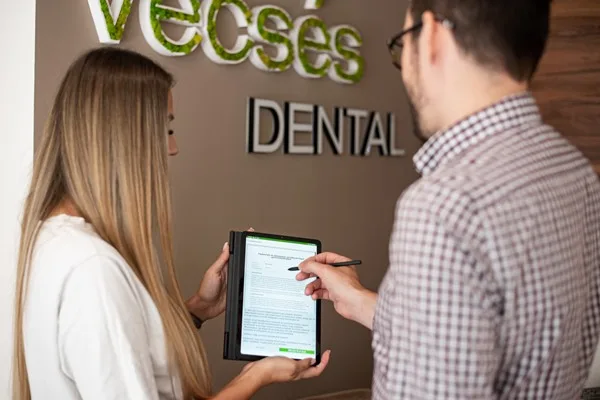 Recepciósunk digitális táblagépen mutatja a dokumentumokat a páciensnek